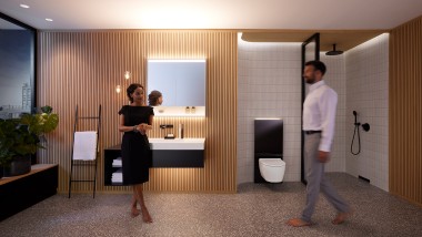 Man and woman in perfectly lit bathroom with Geberit ONE bathroom furniture and ceramic appliances (© Geberit)