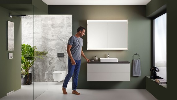 A man stands in a bathroom with high-quality furniture from the Geberit ONE series