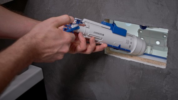 A man installs a Geberit flush valve in a concealed cistern (© Ben Huggler)