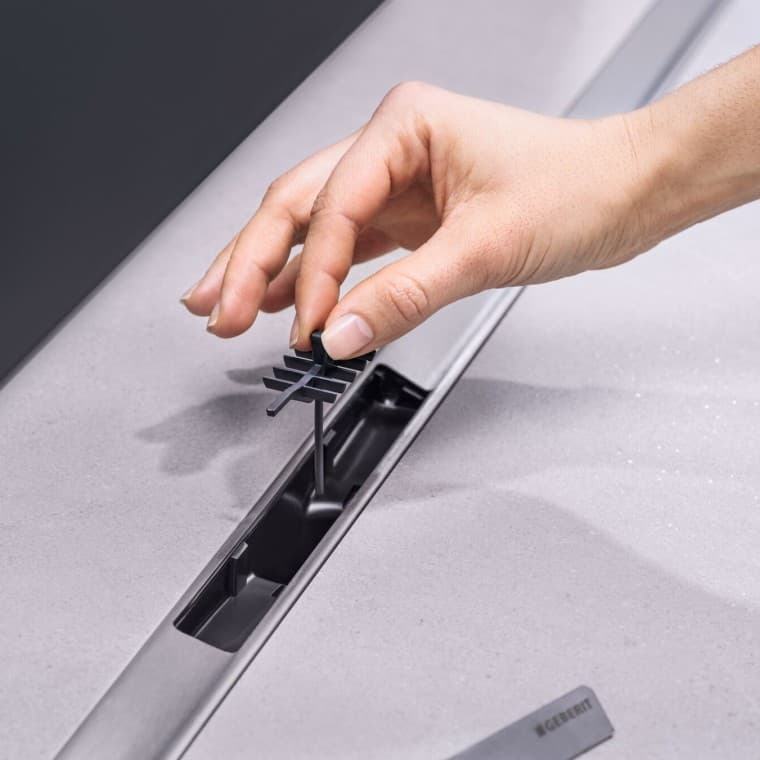 Hand placing a comb insert in the drain Hand placing a comb insert in the drain